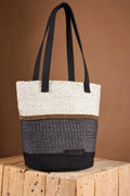 An artisan-made Tote bag with a black and white design on a wooden surface and a brown background