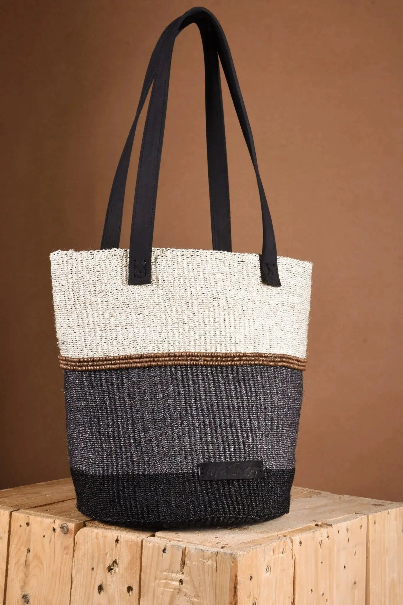 An artisan-made Tote bag with a black and white design on a wooden surface and a brown background