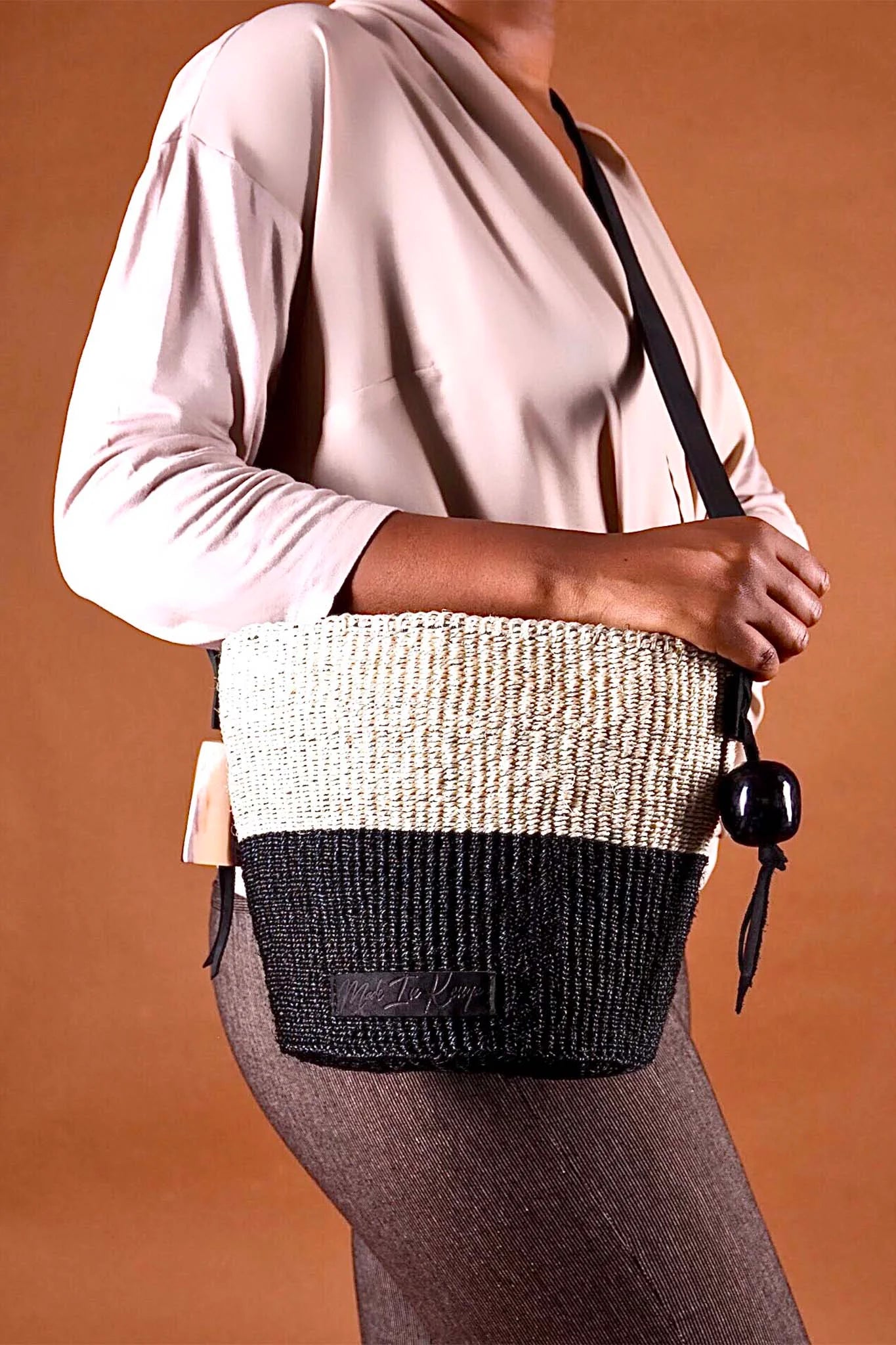 Person holding a two-tone woven handbag with a plain background