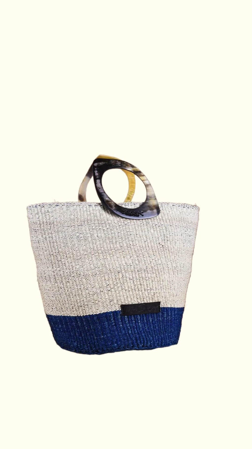 Textured artisan-made handbag with a blue base and tortoiseshell handle on a white background