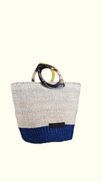 Textured artisan-made handbag with a blue base and tortoiseshell handle on a white background