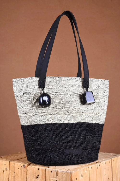 Tote bag with black and white design on a wooden surface and brown background