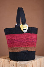 Striped Artisan tote bag with a guitar pick on a wooden block against a brown background. The bag is made from sustainable and natural fibers by a women's artisan initiative