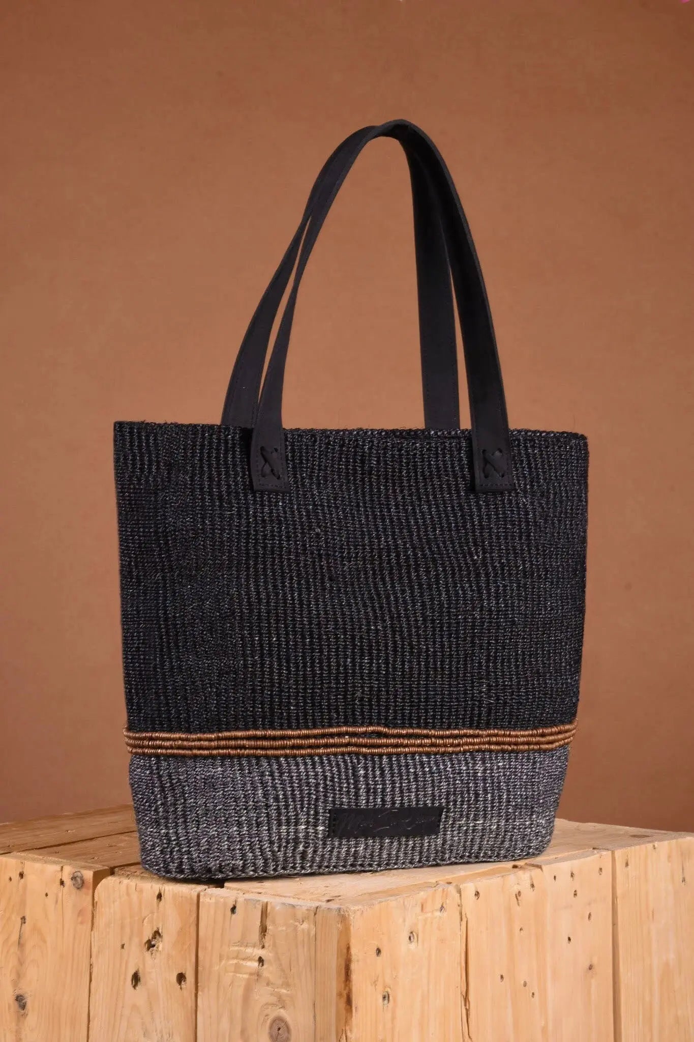 Black textured tote bag on a wooden block with a brown background