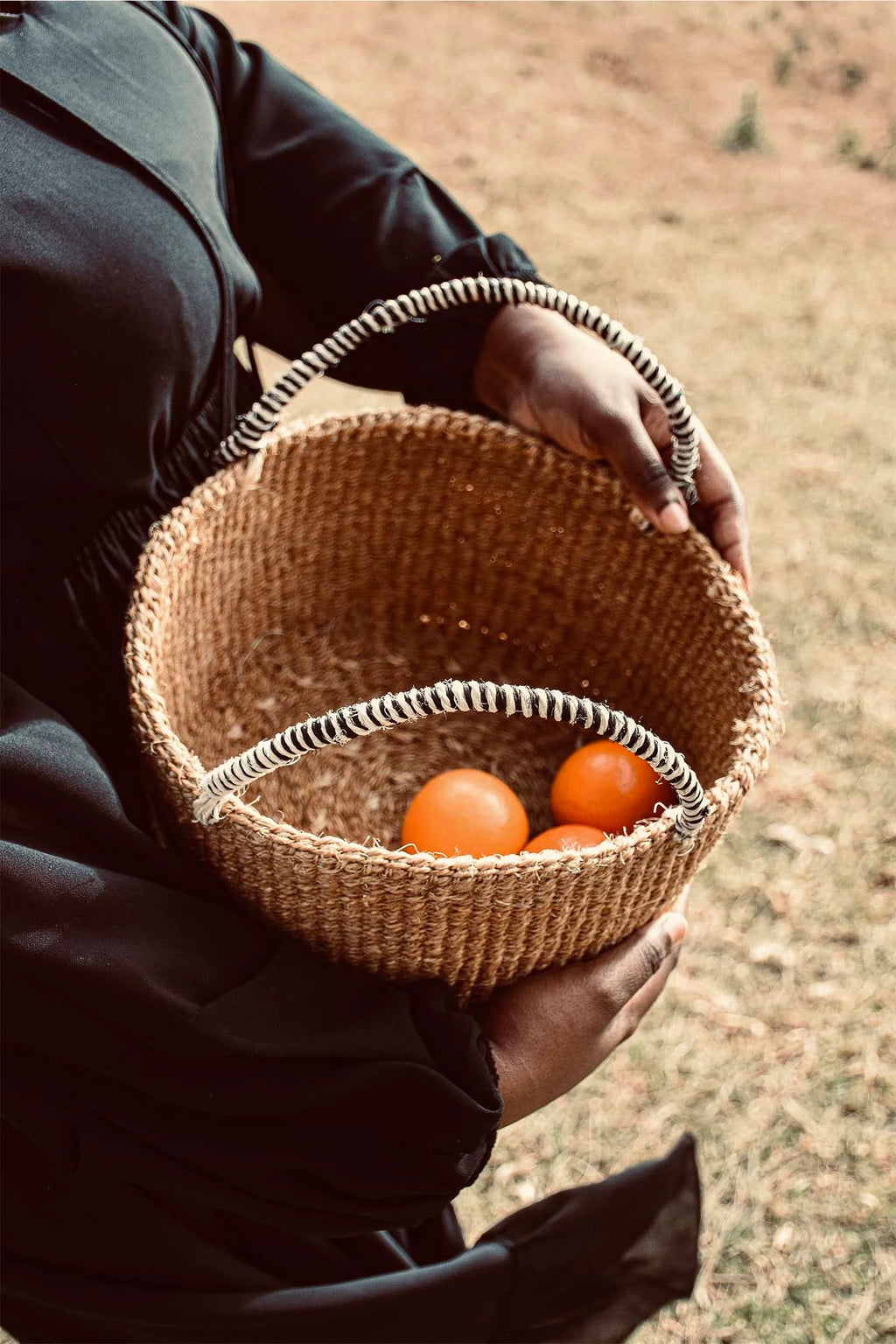 Person holding a woven basket with oranges against a natural background by afrogaze