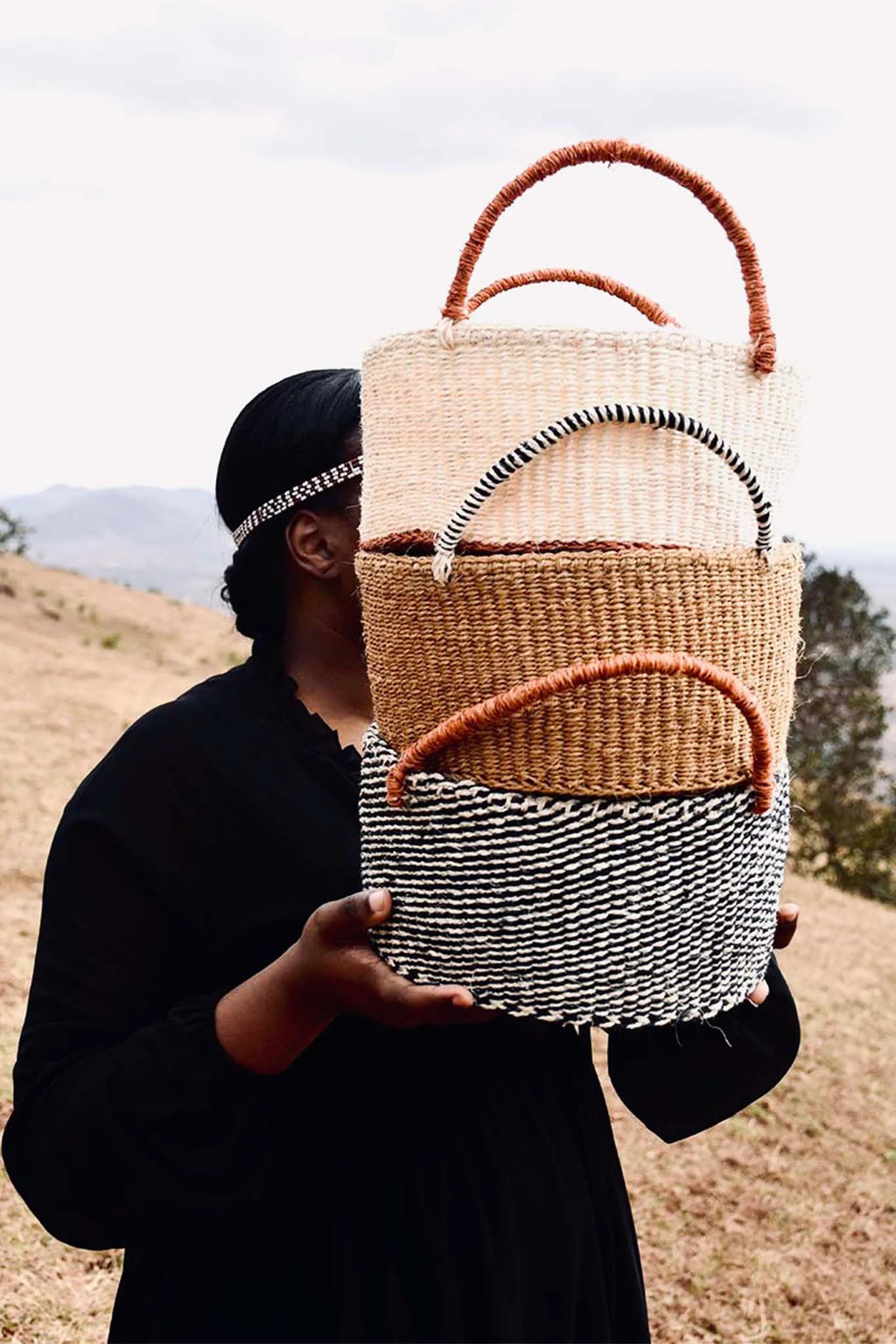 Person holding a woven bag with a striped pattern outdoors- afrogaze storage basket