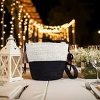 Black and white woven bag on a table with decorative lights in the background