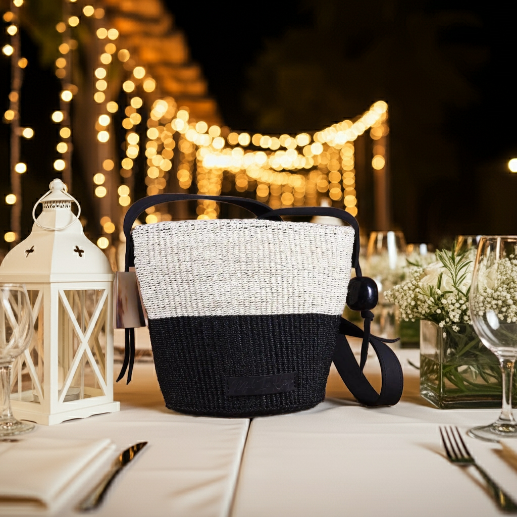 Black and white woven bag on a table with decorative lights in the background